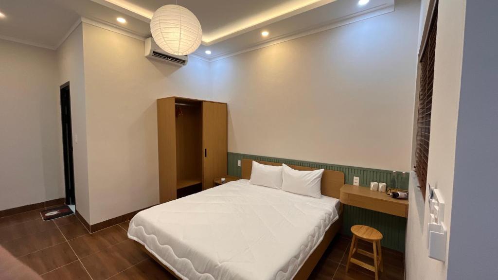 a bedroom with a white bed and a table and stool at Chài Beach Homestay in Ninh Hải