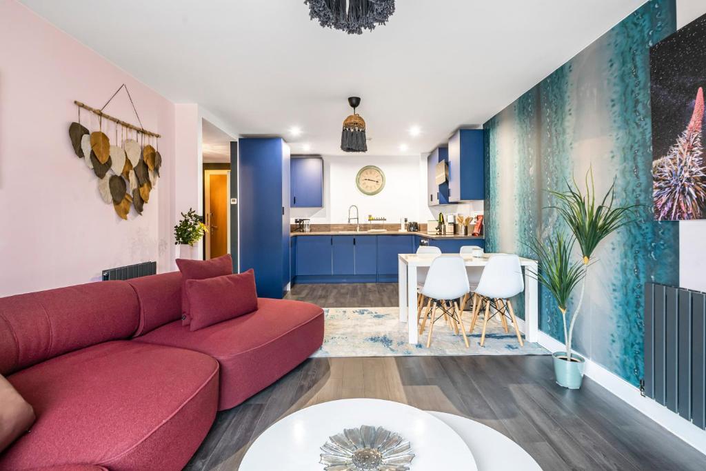 a living room with a red couch and a kitchen at Stylish Flat next2 Wimbledon with a parking in Mitcham Junction