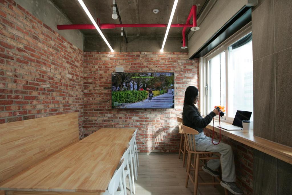a woman sitting at a bar taking a picture at Stay PLAN B in Seoul