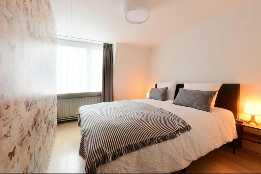 a bedroom with a large bed and a window at Blue City Apartment in Alkmaar