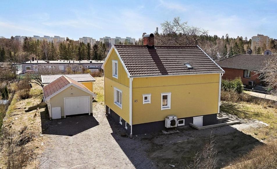 a small yellow house with a garage in a field at The Pearl of Södertälje in Södertälje