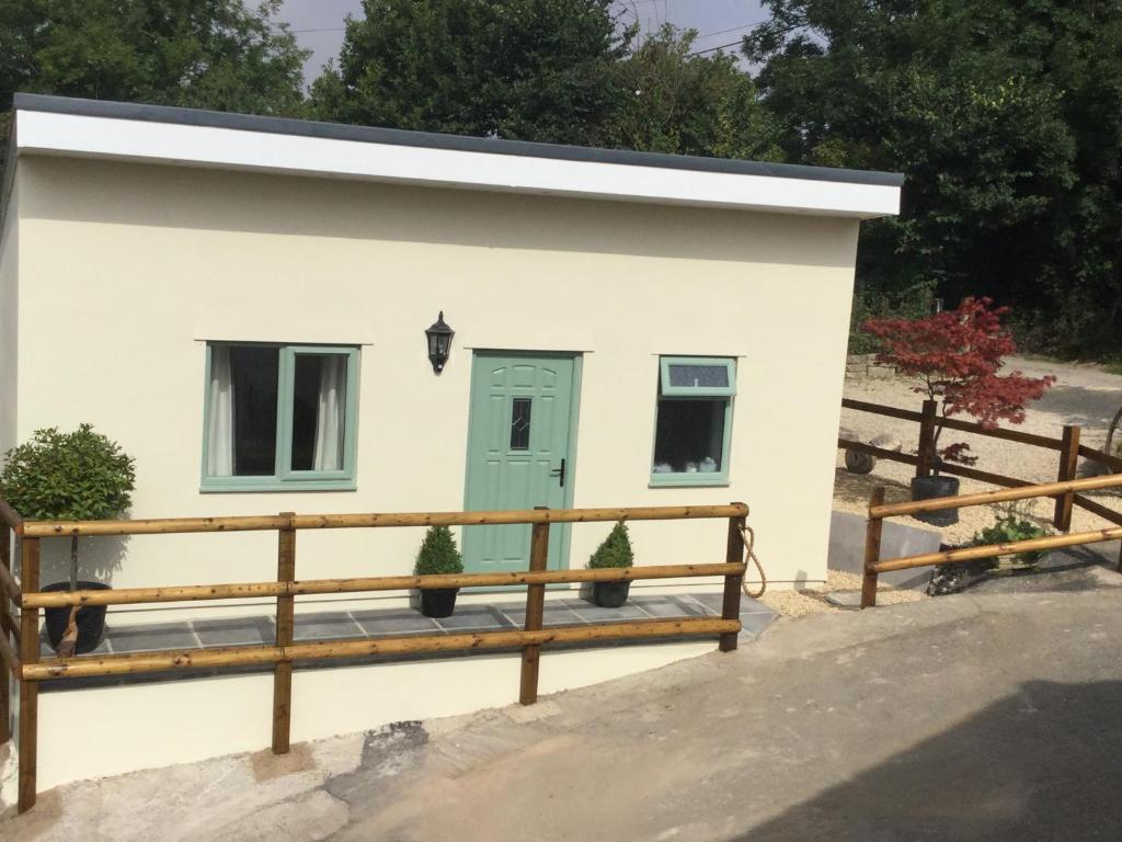 a tiny house with a green door and a wooden fence at Mill Lane Holiday Cottage -Bath in Bath