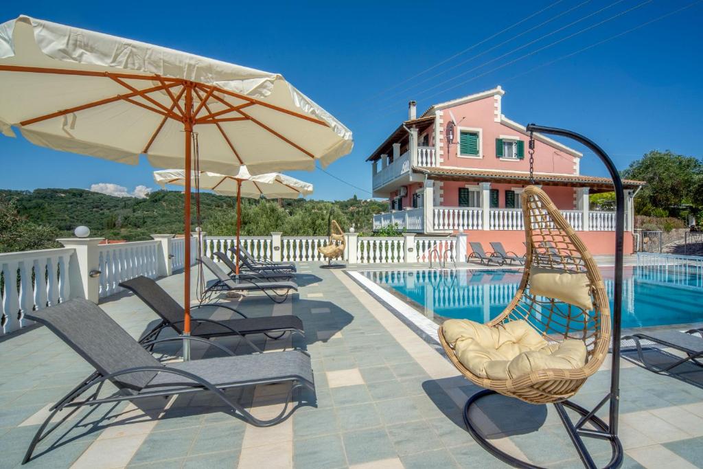 a group of chairs and umbrellas next to a pool at Villa Amalia By Elayan Villas Corfu in Karousádes