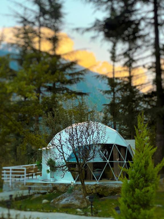 a building with a dome in the middle of trees at The GlampView Resort in Manāli