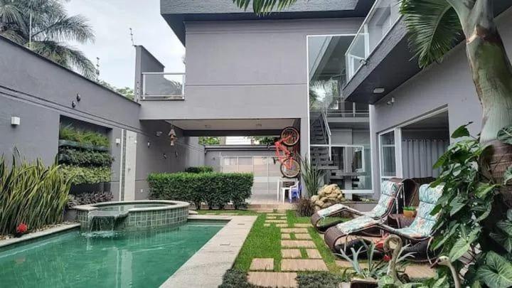 a house with a swimming pool in the yard at Casa de temporada com piscina in Peruíbe