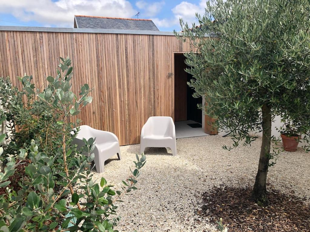 a patio with two white chairs and a tree at Le logis de Niort Appart Hôtel Le bis in Niort