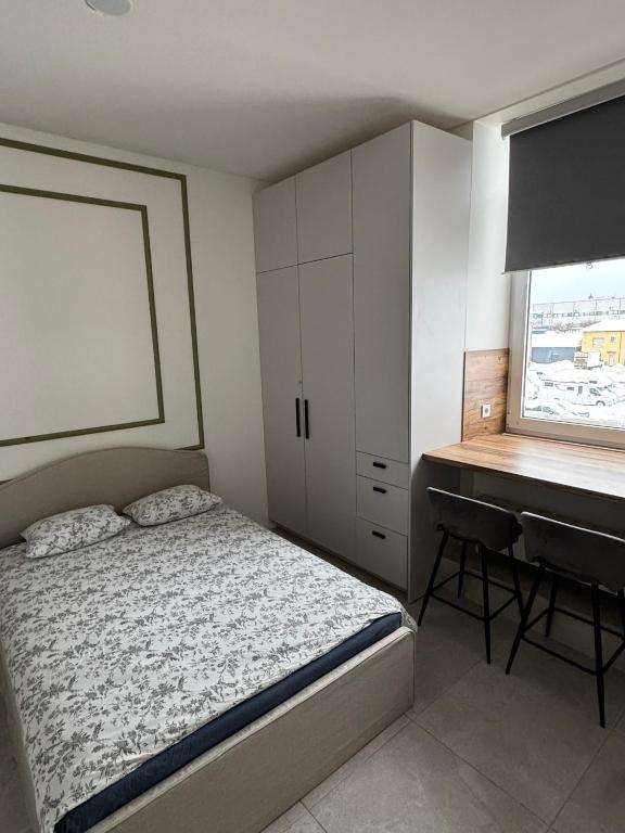 a bedroom with a bed and a desk next to a window at 16 Airport Apartment in Vilnius