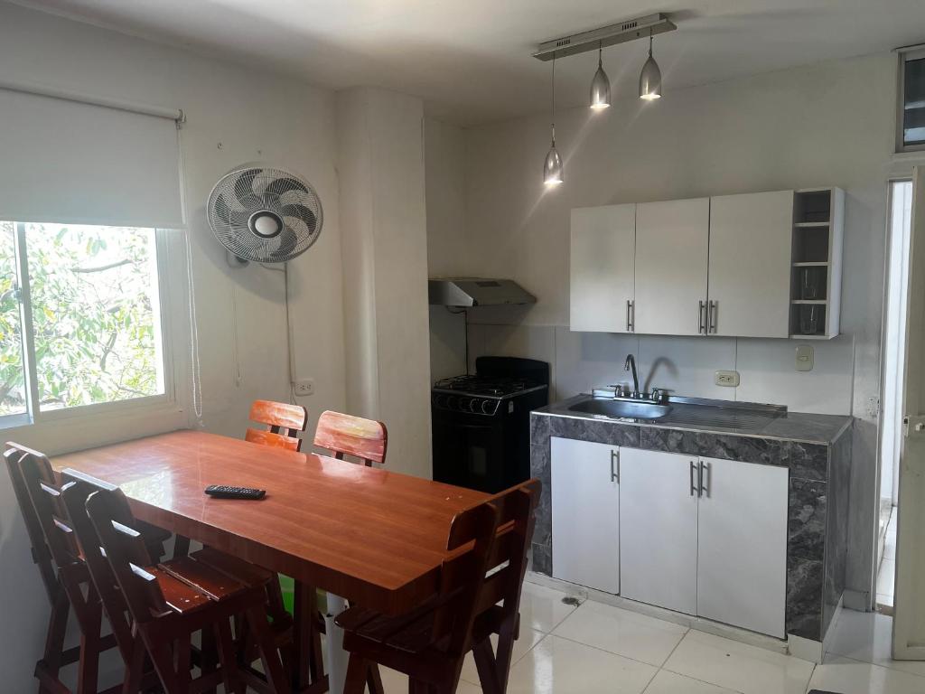 a kitchen with a wooden table and chairs and a kitchen with white cabinets at Playa Los Cocos Apat 2 y 3 in Santa Marta