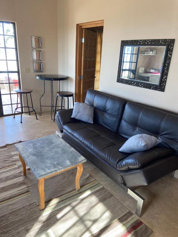 a living room with a black leather couch and a table at Casitas Vista del Aguila in Todos Santos