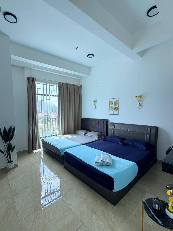 two beds in a room with blue lighting at D'Anggun Studio in Gua Musang