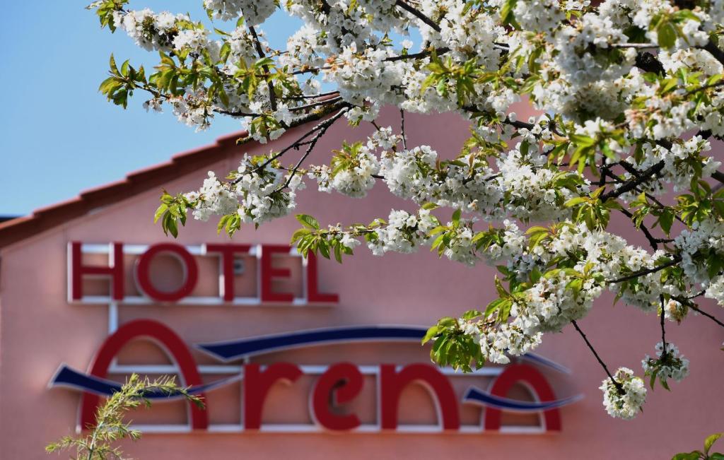 um sinal para um hotel é visto atrás de uma árvore florida em Arena Stadt München em Munique