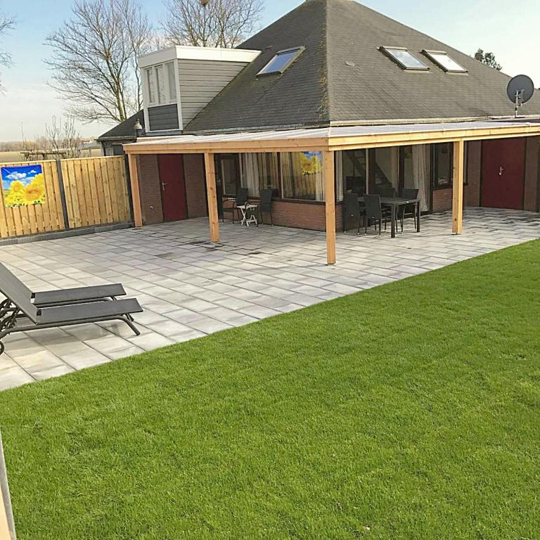 a house with a patio with a bench on a lawn at Zeeuwse Luwte in Stavenisse
