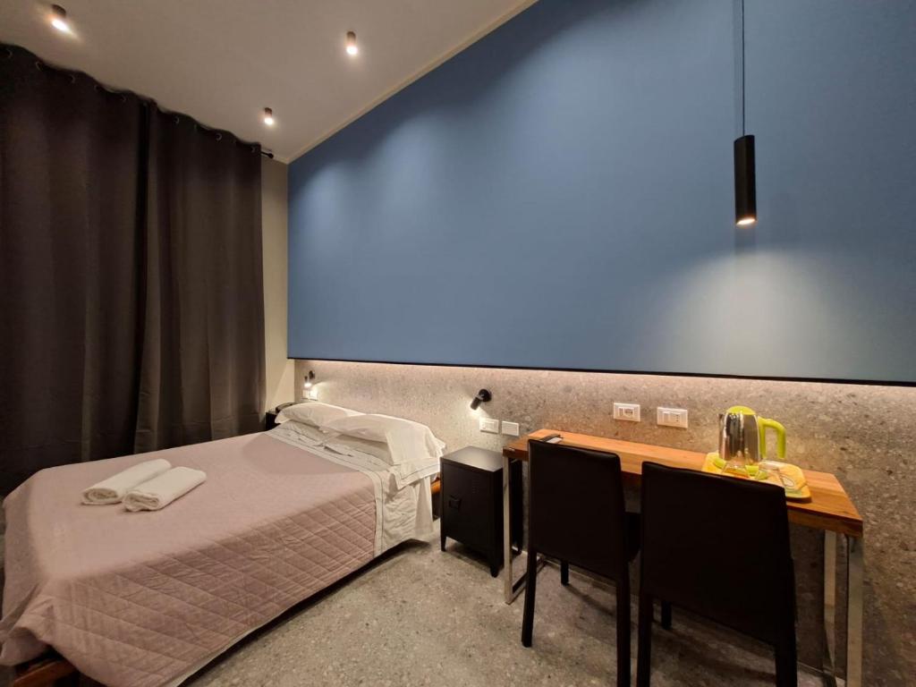 a bedroom with a bed and a desk with chairs at Hotel Calypso in Milan