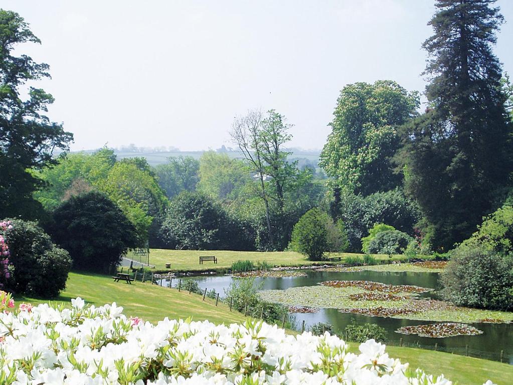 a garden with a pond with flowers in it at Rosecraddoc Manor - Heron in Saint Cleer