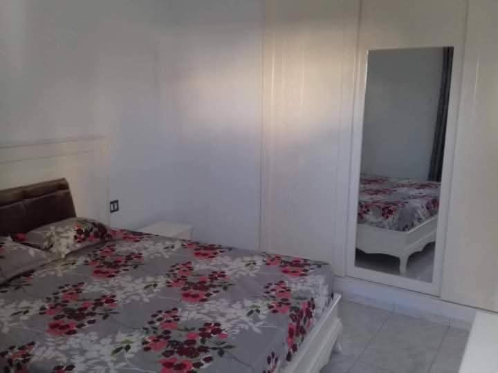 a bedroom with a bed and a mirror at CHEZ ALAA Kelibia in Kelibia