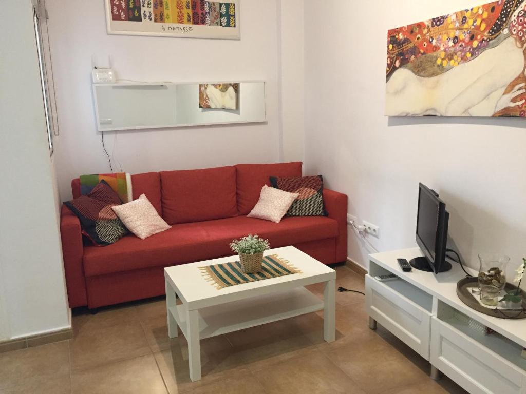 a living room with a red couch and a coffee table at San Juan Apartamento in Jerez de la Frontera