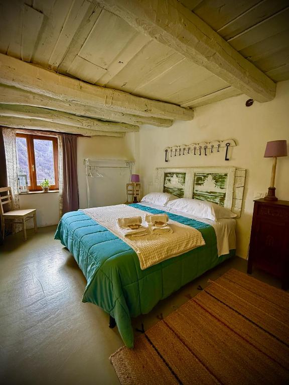 a bedroom with a large bed with a green blanket at Viandanti, Artisti e Sognatori in Comano