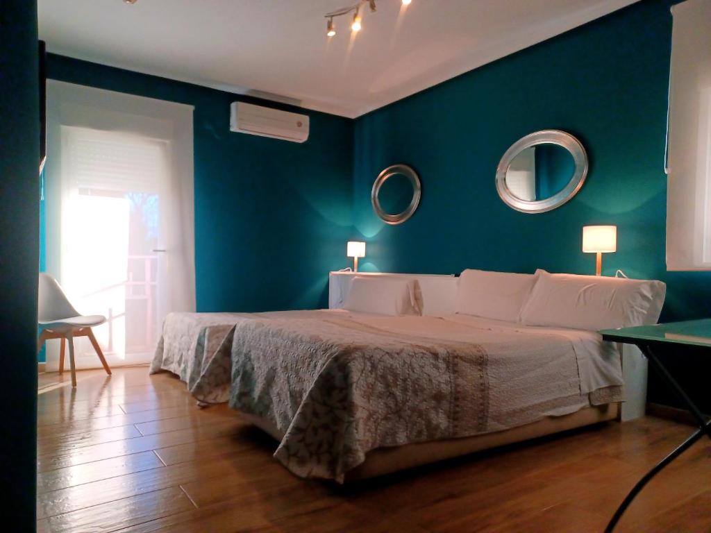 a blue bedroom with a bed and two mirrors at C&H Aravaca Garden in Madrid