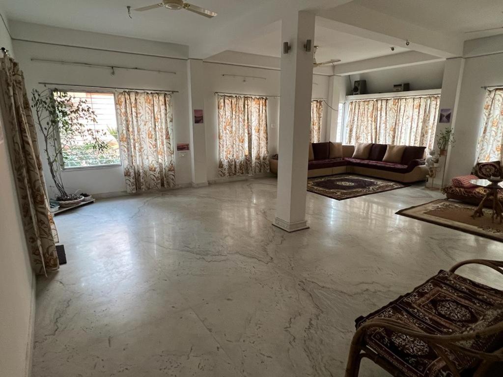 a large living room with a couch and windows at Pappu in Siliguri