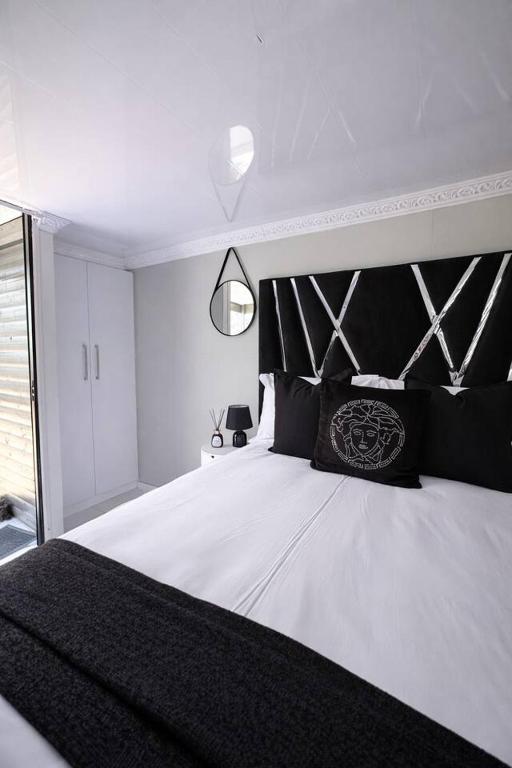 a bedroom with a large bed with a black headboard at Elite Luxe Cabin Suite in Welkom