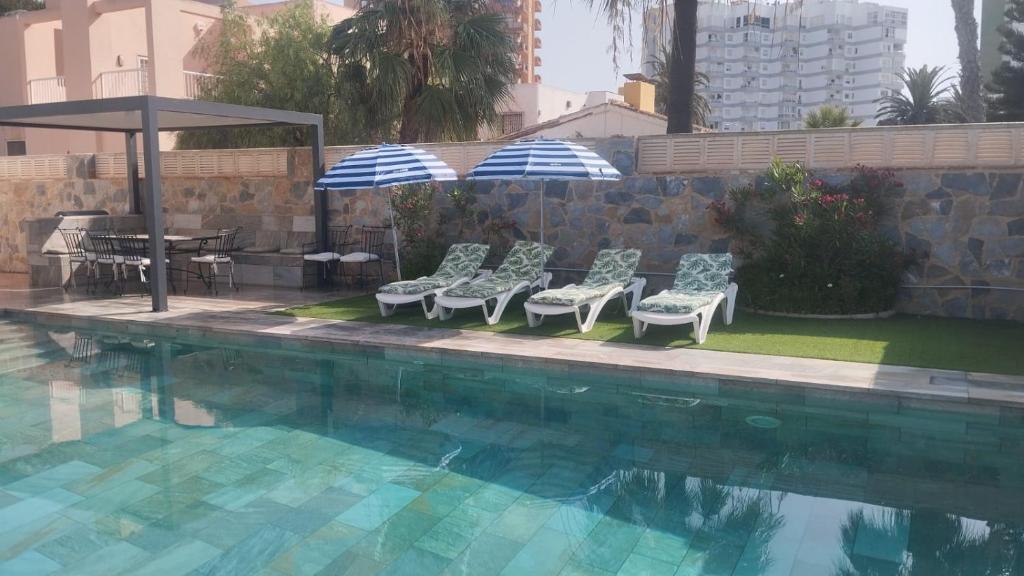 a group of chairs and umbrellas next to a pool at Villa Sol in Roquetas de Mar