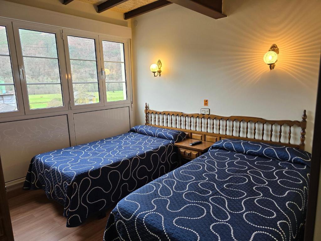 a hotel room with two beds and a window at Pensión La Unión in Trevías