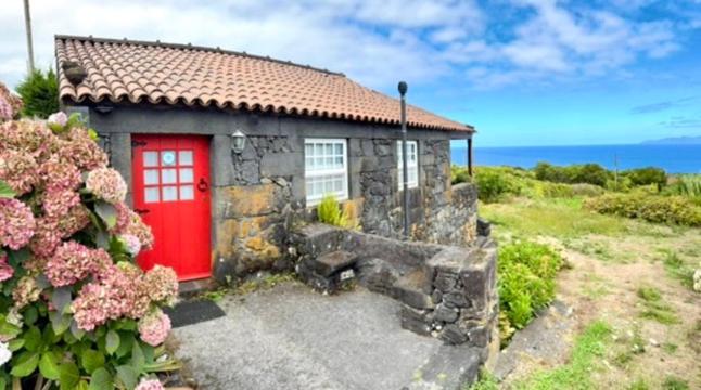 a small house with a red door in a field at Casa de Santana in Santana