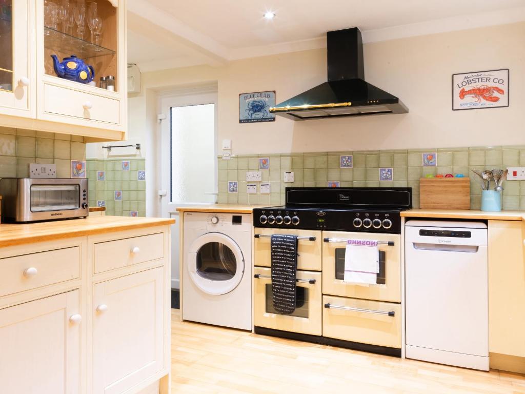 a kitchen with a stove and a washer and dryer at White Stones in Burford