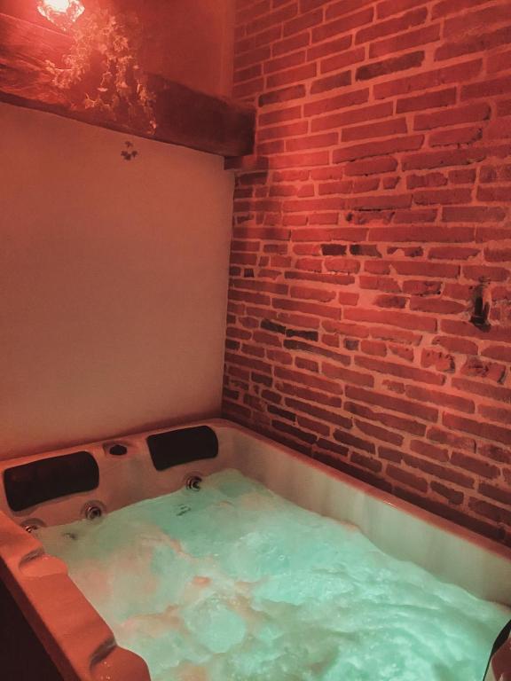 a hot tub in a room with a brick wall at Briques & Bulles in Montauban