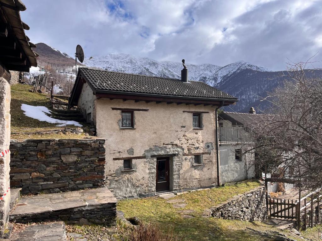 an old stone house with mountains in the background at Rustico Indéman in Gambarogno