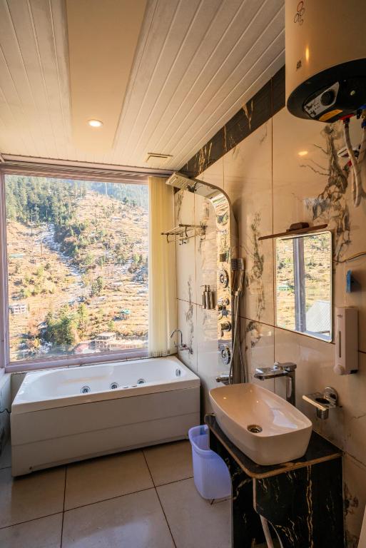 a bathroom with a tub and a sink and a window at Sunrise Farm Stays in Jibhi