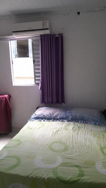 a bed in a room with a window and a bedspread at Casa de adao in Guarujá