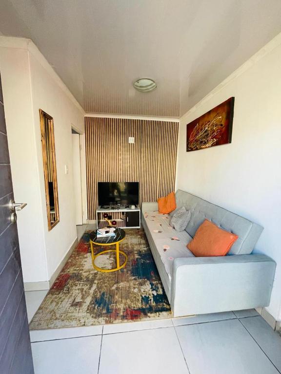 a living room with a couch and a tv at Kay's Guest House in Kraaifontein