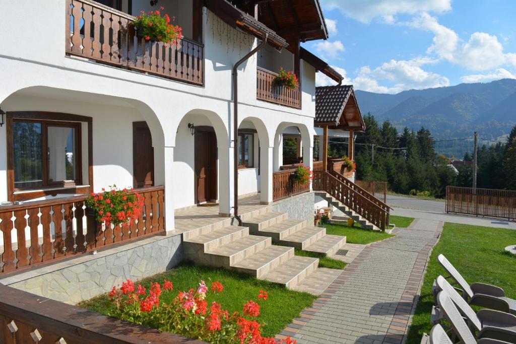 a building with stairs and flowers in front of it at Pensiunea Encian in Colibiţa