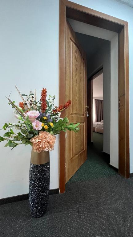 a vase with a bouquet of flowers in a room at Central Hotel with Rooftop Terrace in Bucharest