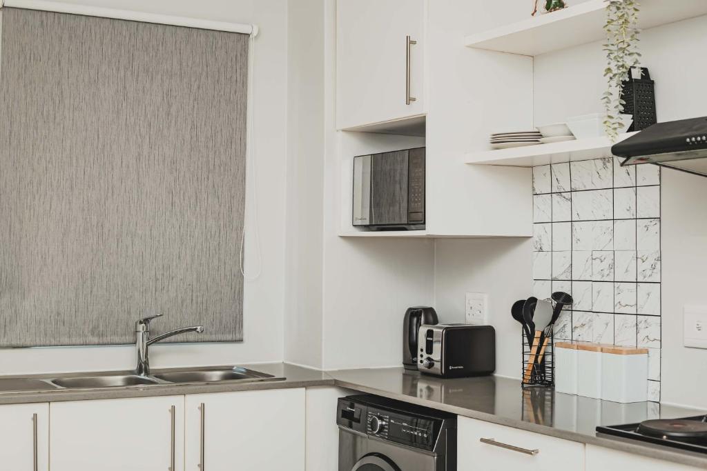 a white kitchen with a sink and a microwave at Ballito Exotic Lifestyle in Ballito