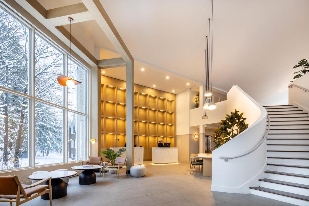 a lobby of a building with a staircase and tables and chairs at Auberge de la Montagne Coupée in Saint-Jean-de-Matha