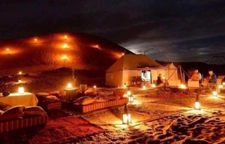a group of people standing in a tent at night at Desert Berber Fire-Camp in Merzouga