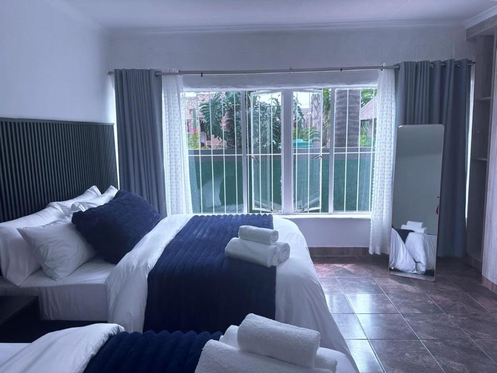 a bedroom with a blue and white bed and a window at SA Guest House in Roodepoort