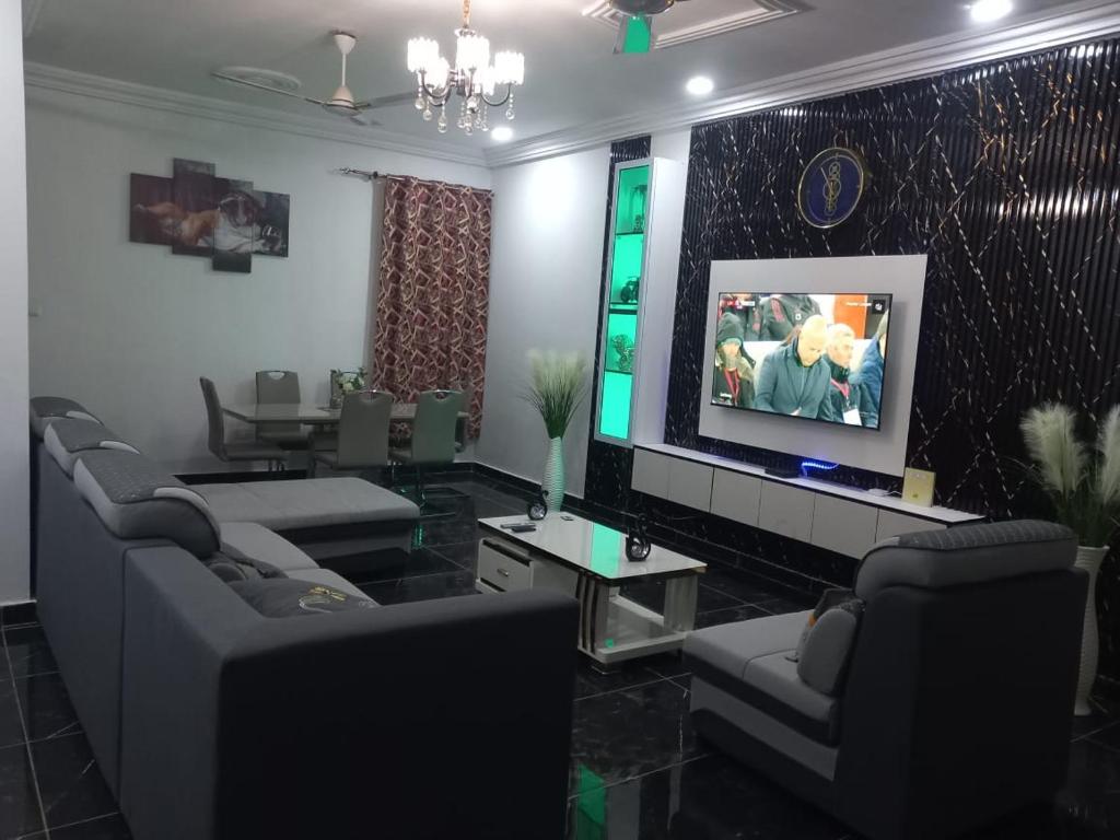 salon z kanapami i telewizorem z płaskim ekranem w obiekcie EMA Apartment w mieście Kokrobite