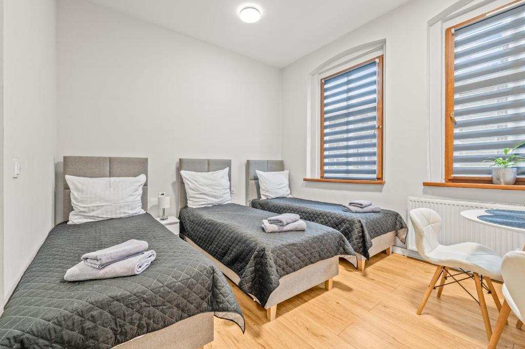 a bedroom with two beds and a table and windows at Central Platinum Apartments 4 in Rybnik