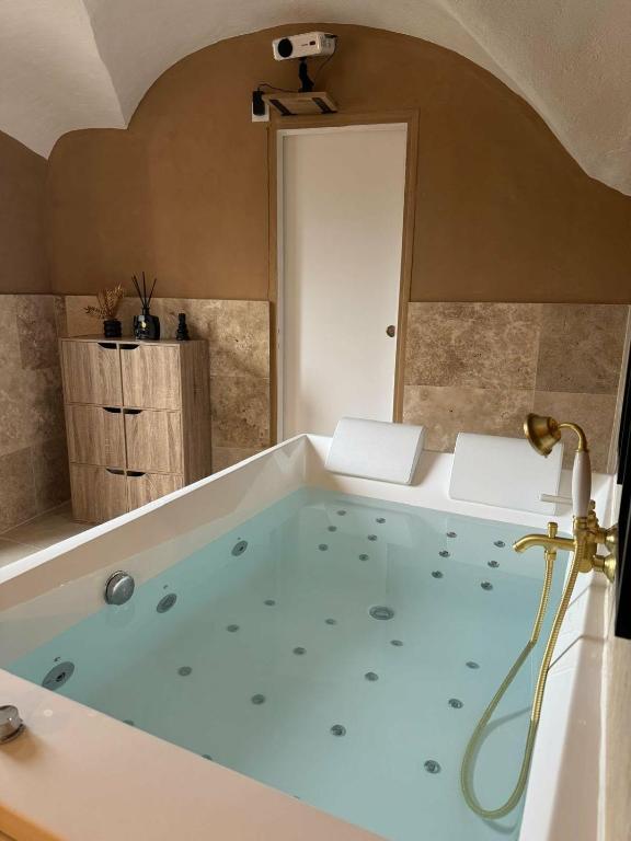 a bathroom with a large tub with blue water at Les Voûtes Secrètes - Love Room avec Balnéo à Bras in Bras