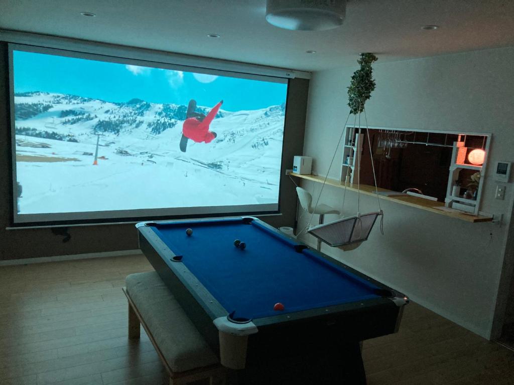 a large screen with a pool table in front of a tv at Lhouseー遊べる宿ビリヤード 大型スクリーン 岡山駅徒歩15分 in Okayama