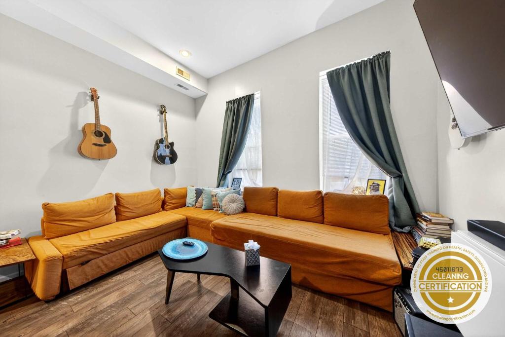 a living room with a couch and a guitar on the wall at Stylish STL Gem ABODEbucks in Saint Louis
