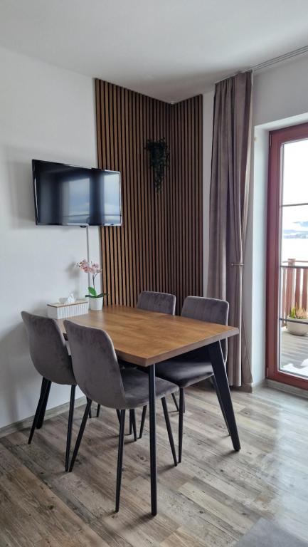 a dining room table with chairs and a television on the wall at Apartmán Kovadlina 5 - Kovářov, výhled na Lipno in Frymburk