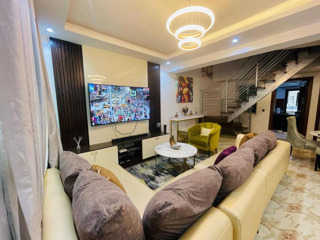 a living room with a large couch and a television at Blue Bell Suites in Lekki