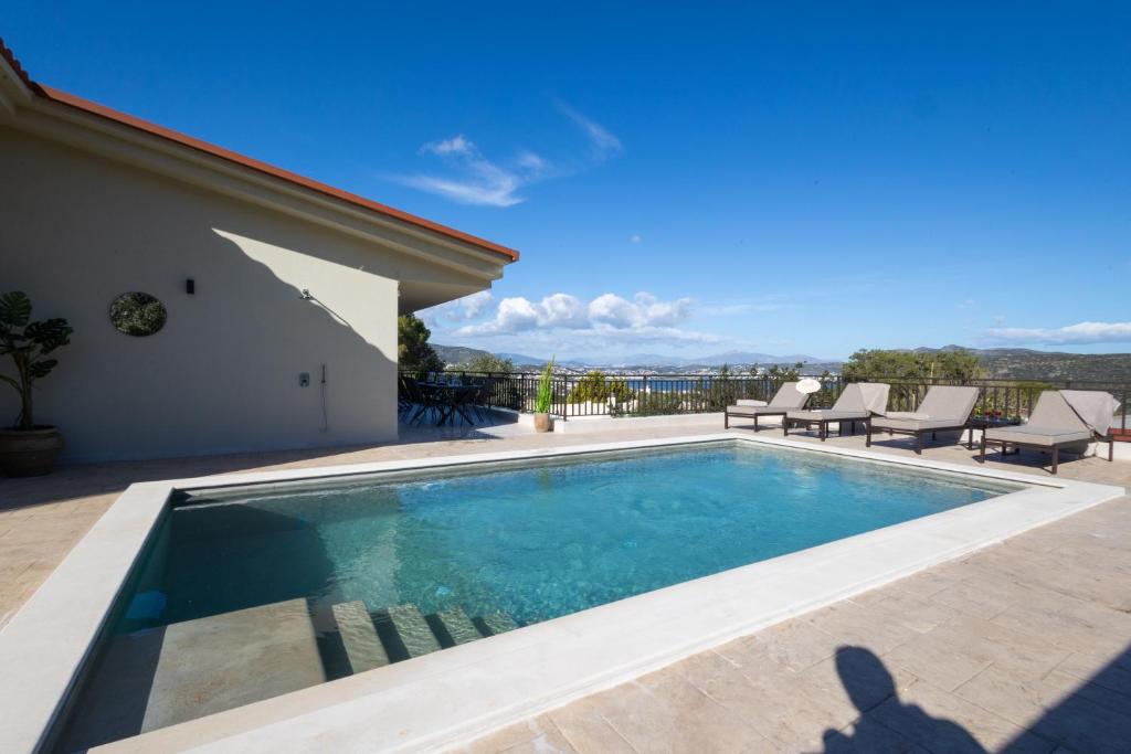 a swimming pool with chairs and a house at Villa Keyd Mare in Porto Rafti