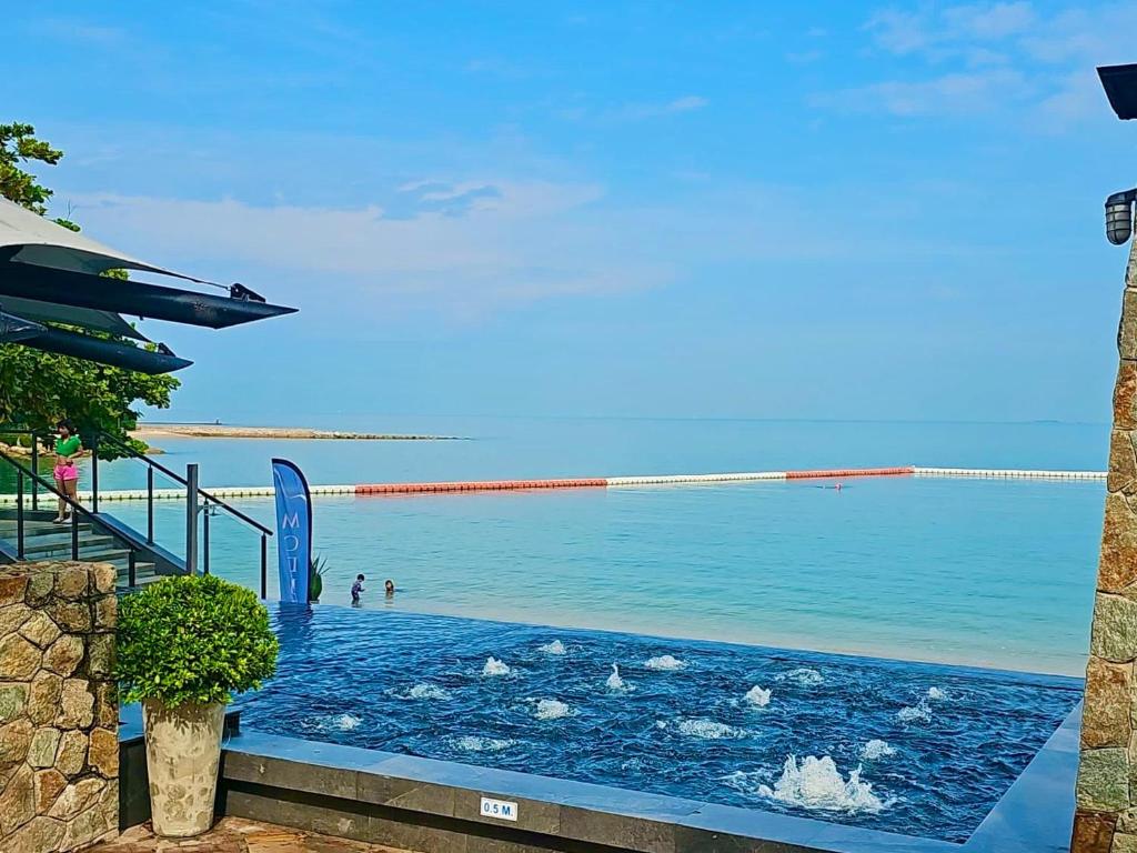 a swimming pool on the beach with people in the water at Modus Pattaya Beachfront Apartment in North Pattaya
