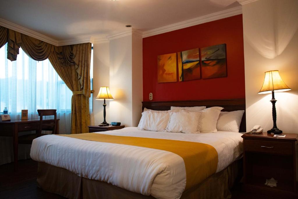 a bedroom with a large bed with a red wall at Quo Vadis Hotel in Loja