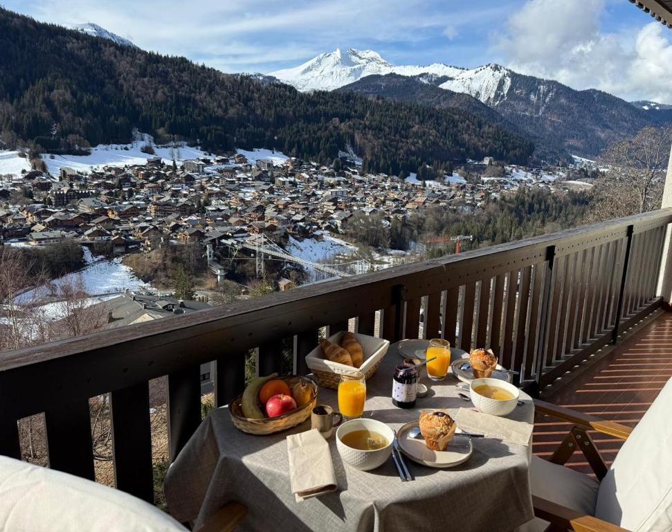 a table with food on top of a balcony with mountains at Morz'Inn Vue panoramique sur les montagnes in Morzine